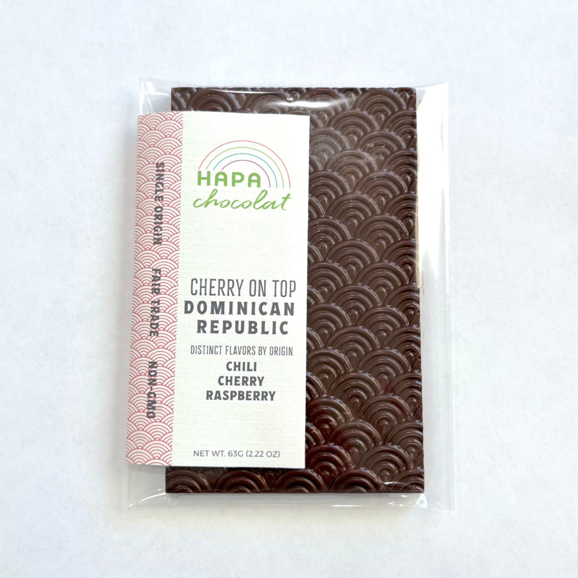 A dark chocolate bar in clear cello packaging with a paper sticker label on a white background.