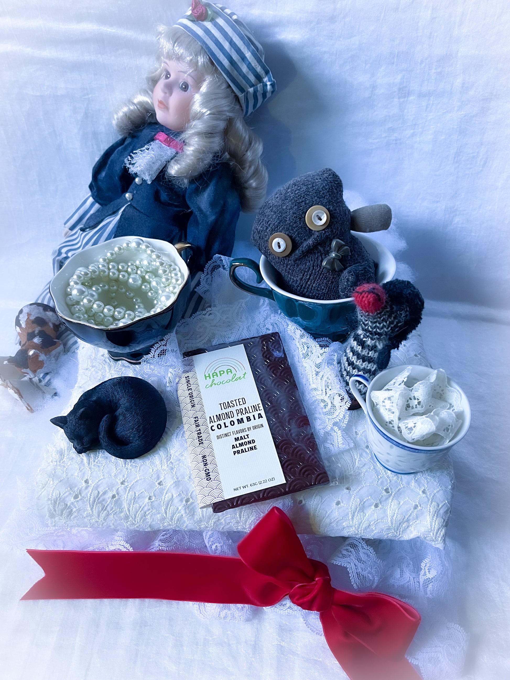 Toys and a doll having a tea party with a dark chocolate bar and lots of lae.