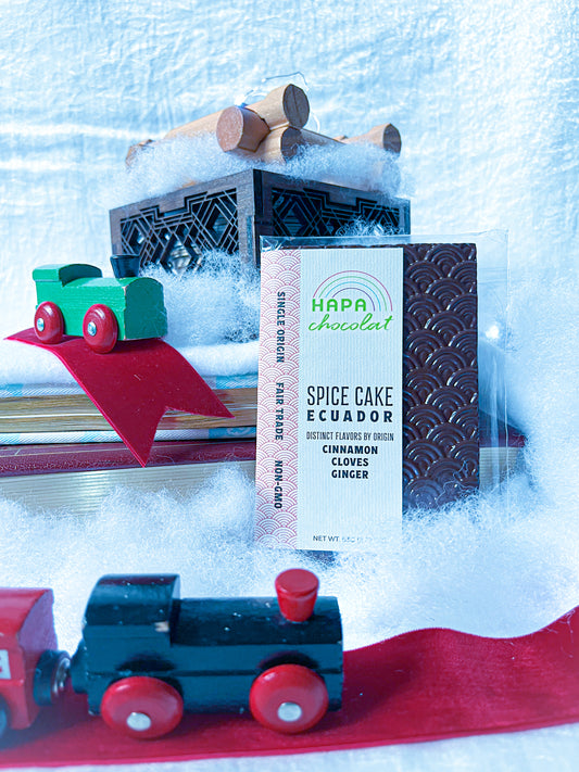 A chocolate bar in cotton snow with two wooden trains and a small log cabin on a book.