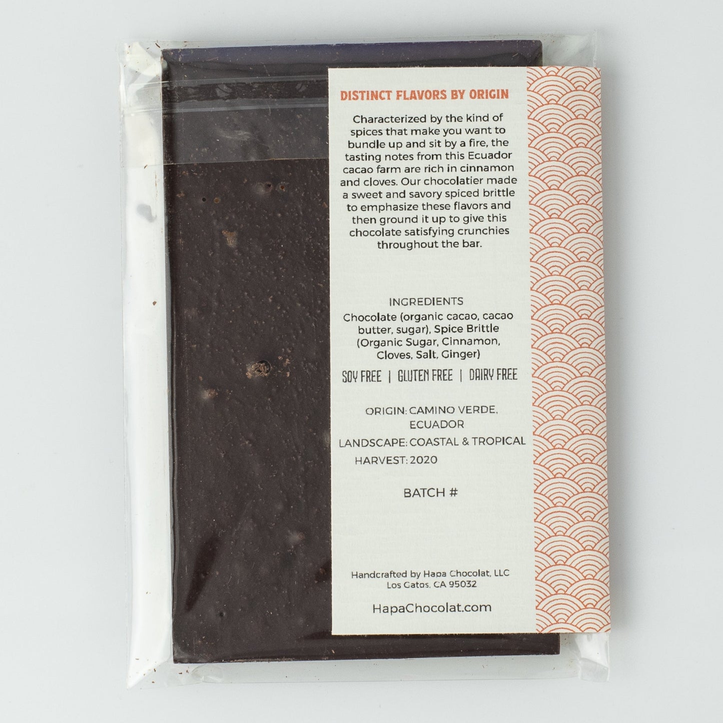 The backside of the dark chocolate bar in an eco-cello bag with a back seal showing and the ivory label with the description on it.