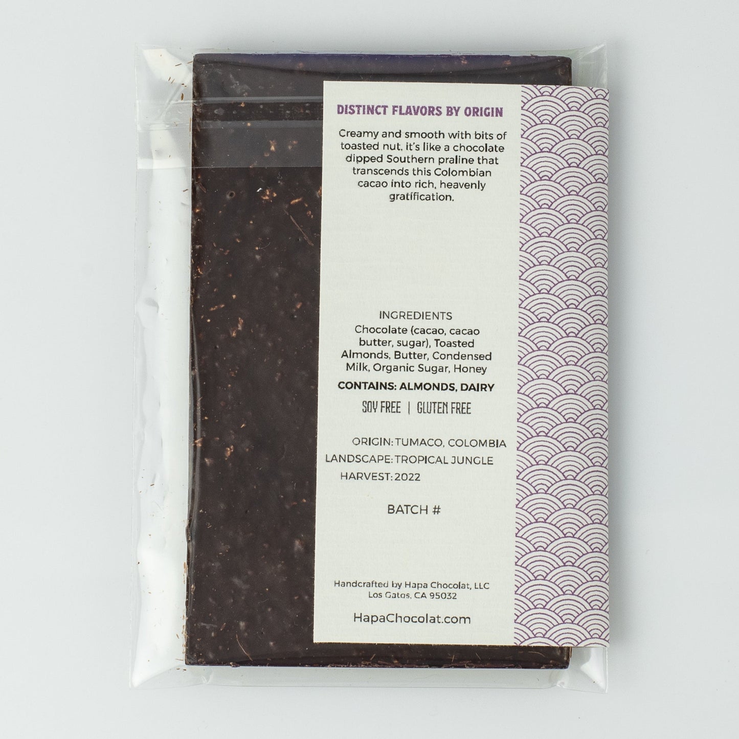 The backside of the dark chocolate bar in an eco-cello bag with a back seal showing and the ivory label with the description on it.