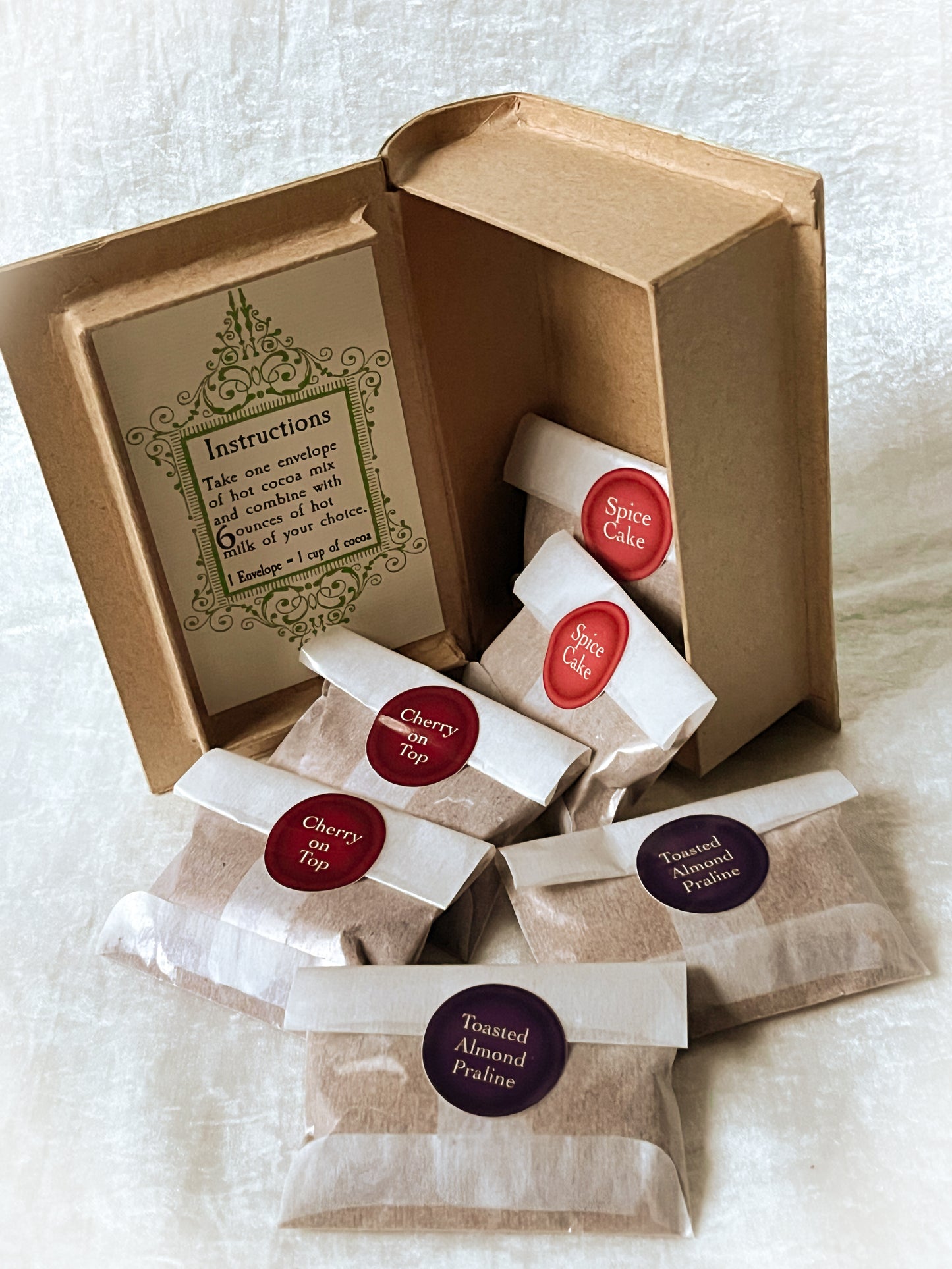 Inside of a book box with 6 packets of hot cocoa mix with different flavor stickers.