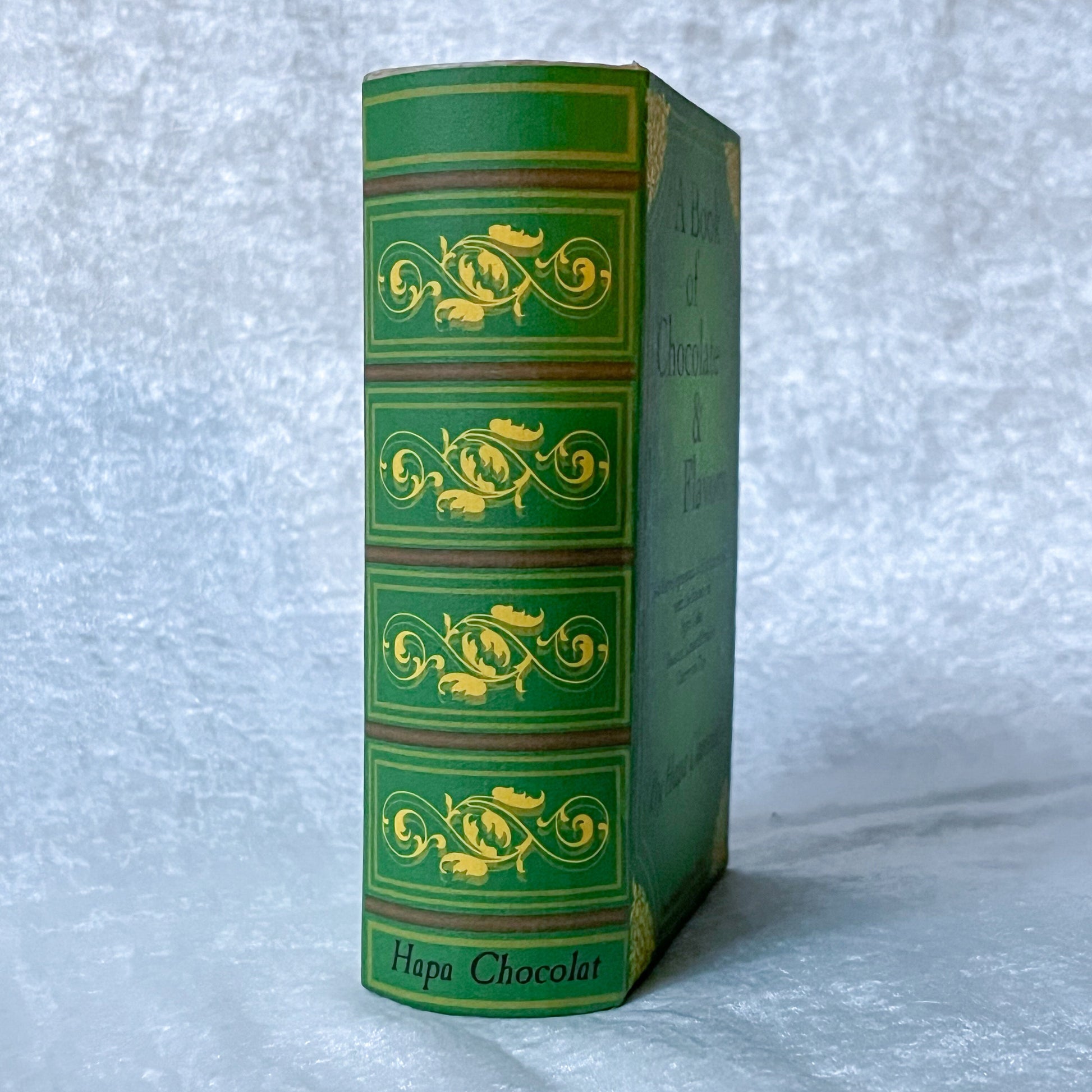 The spine of a green book with gold swirls on a white background.