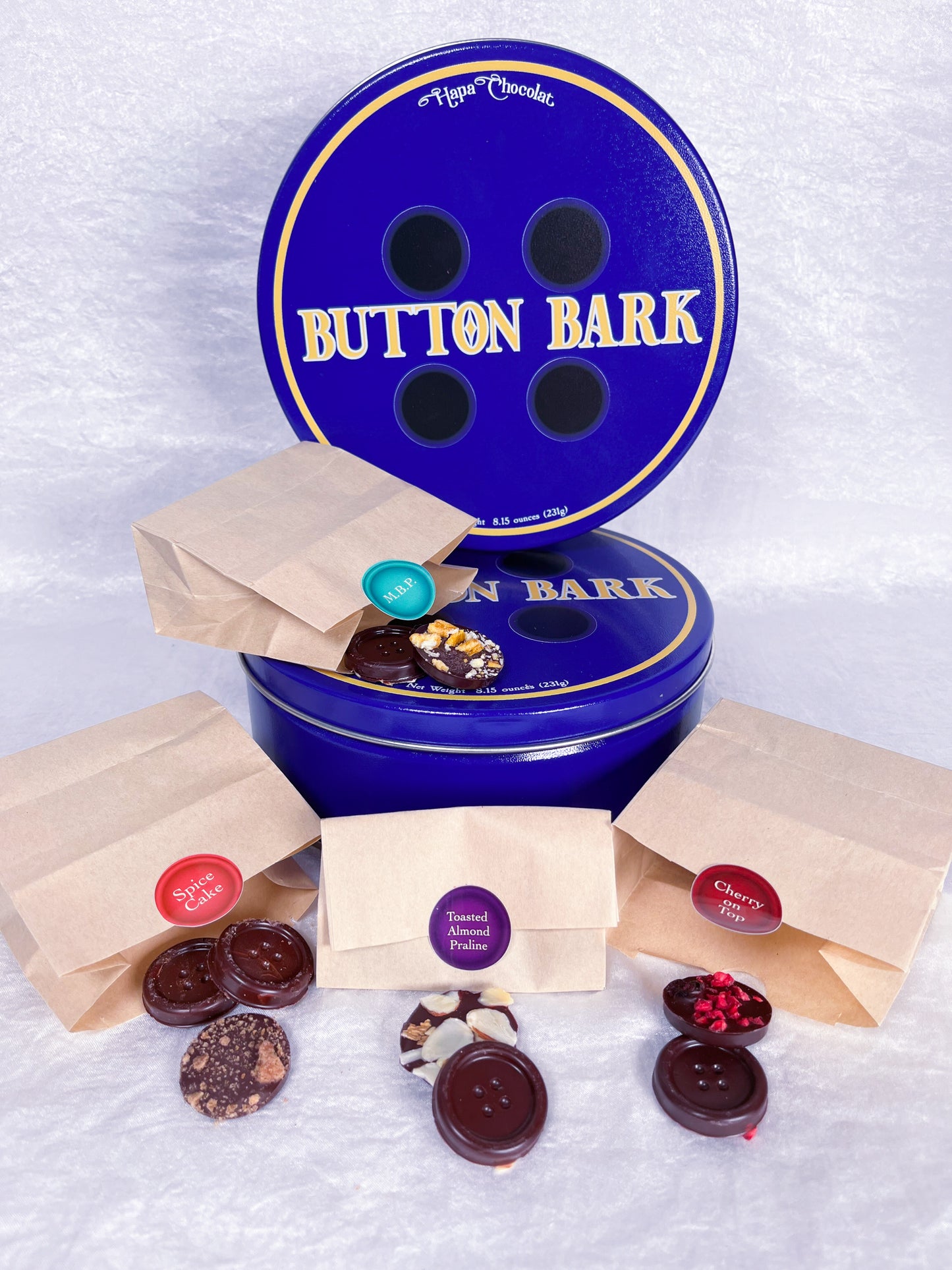 Two blue tins with four little paper bags of different chocolate buttons