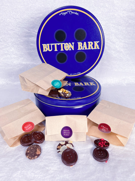 Two blue tins with four little paper bags of different chocolate buttons
