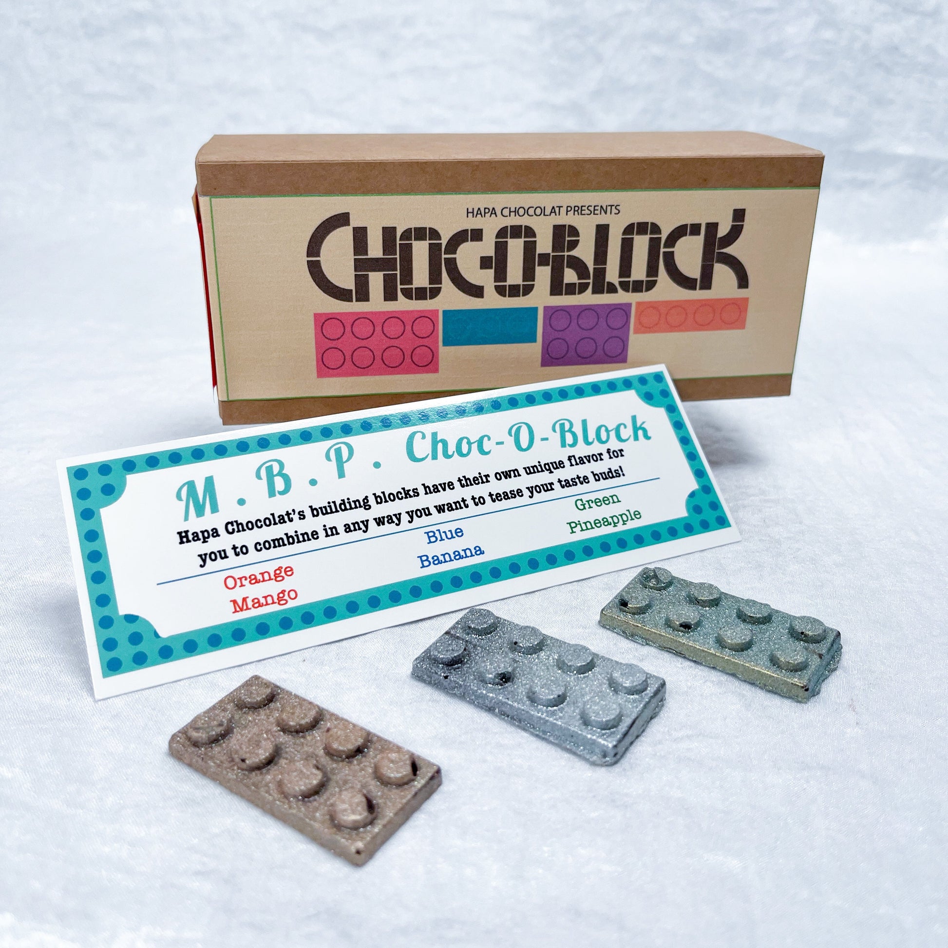 A brown packaging box with a information guide and 3 different colored blocks